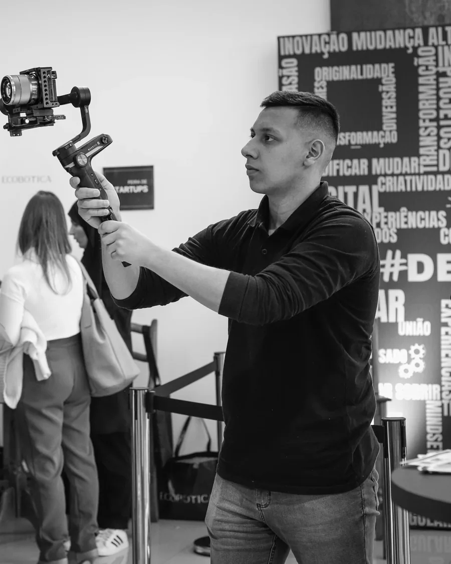 João Lima gravando com câmera e estabilizador em uma feira de startups