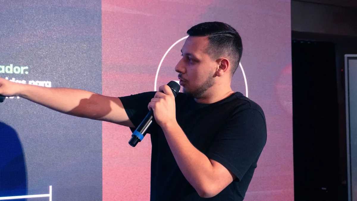 João Lima apontando para o telão durante a palestra no High Level Experience
